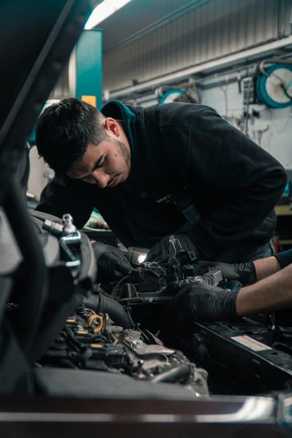 Mecànic jove amb guants negres treballant al motor d'un vehicle en un taller mecànic