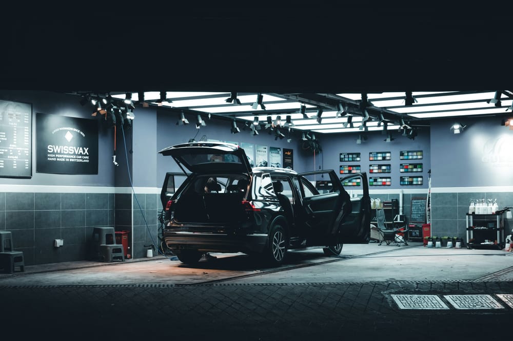 Vehicle SUV negre en un centre de detailing amb les portes obertes sota il·luminació professional